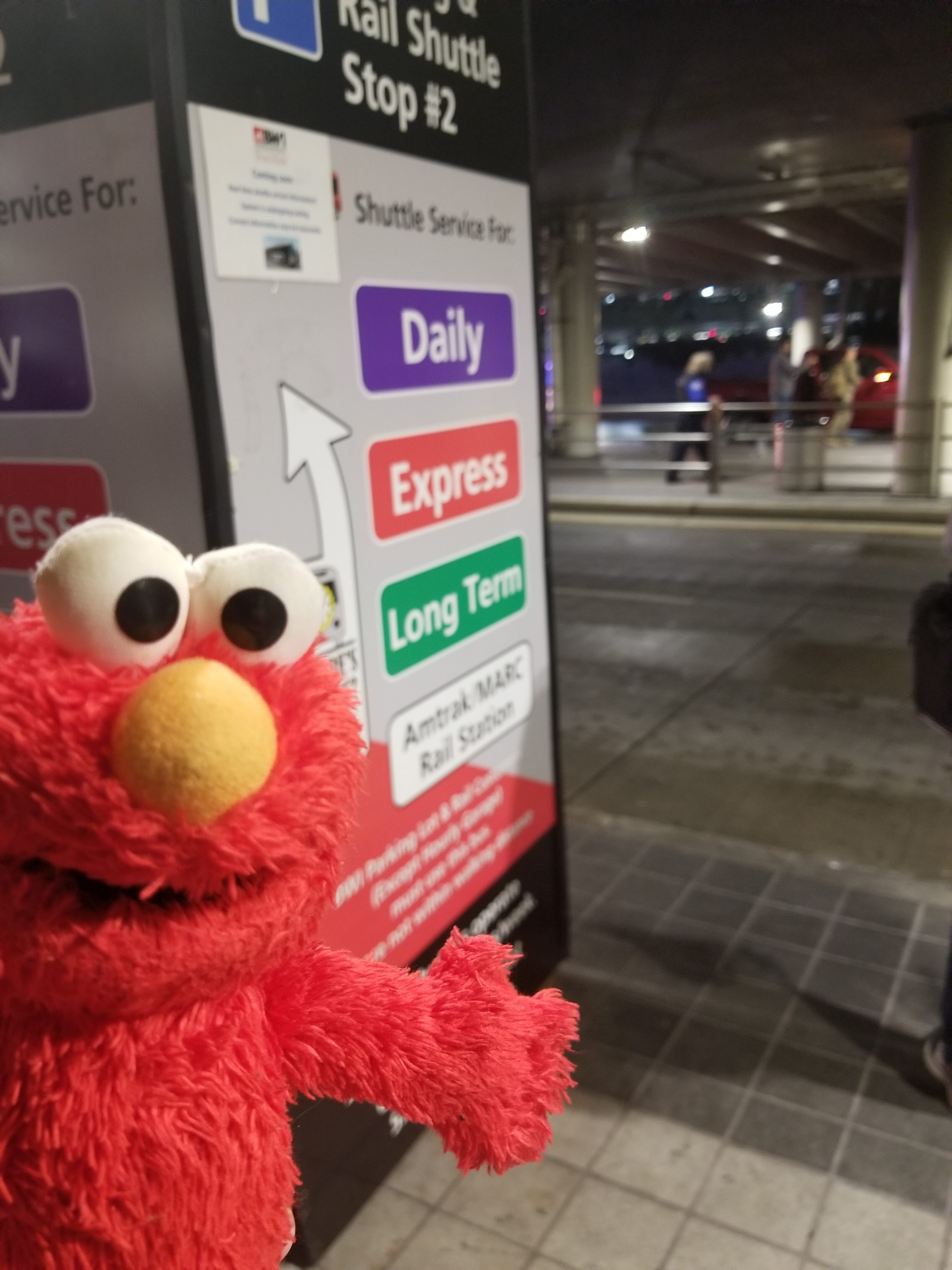 Elmo waits at the bus stop for the bus back to the parking lot